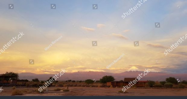 Las luces del atardecer en el paisaje árido y desolado del desierto de Atacama con los picos de los volcanes nevados de la cordillera de los Andes en el fondo. Autor y Copyright Marco Ramerini